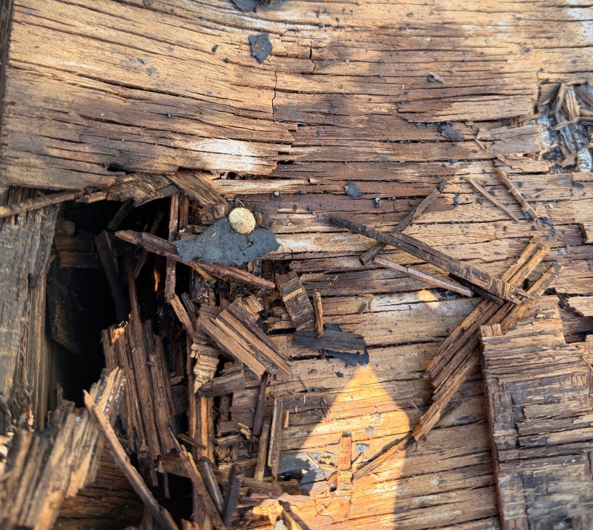 Rotted roof decking with a hole through to the attic
